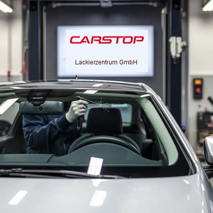 Mechaniker repariert beschädigte Windschutzscheibe eines Autos in einer Werkstatt mit CarStop-Logo im Hintergrund.Mechaniker repariert beschädigte Windschutzscheibe eines Autos in einer Werkstatt mit CarStop-Logo im Hintergrund.