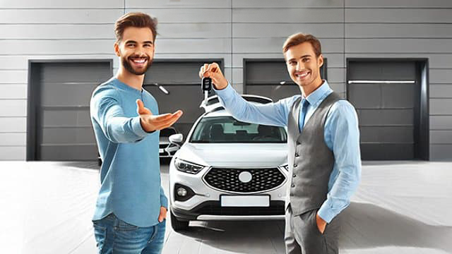 Autohaus-Mitarbeiter übergibt einem Kunden einen Autoschlüssel für einen Ersatzwagen.